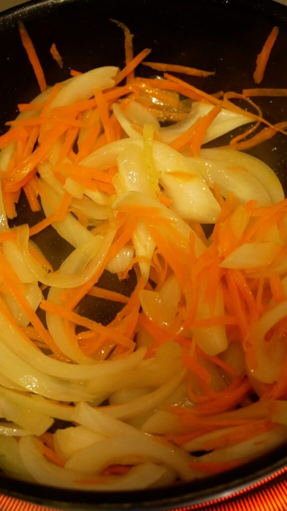 フライパンで玉ねぎとにんじんを炒めている様子