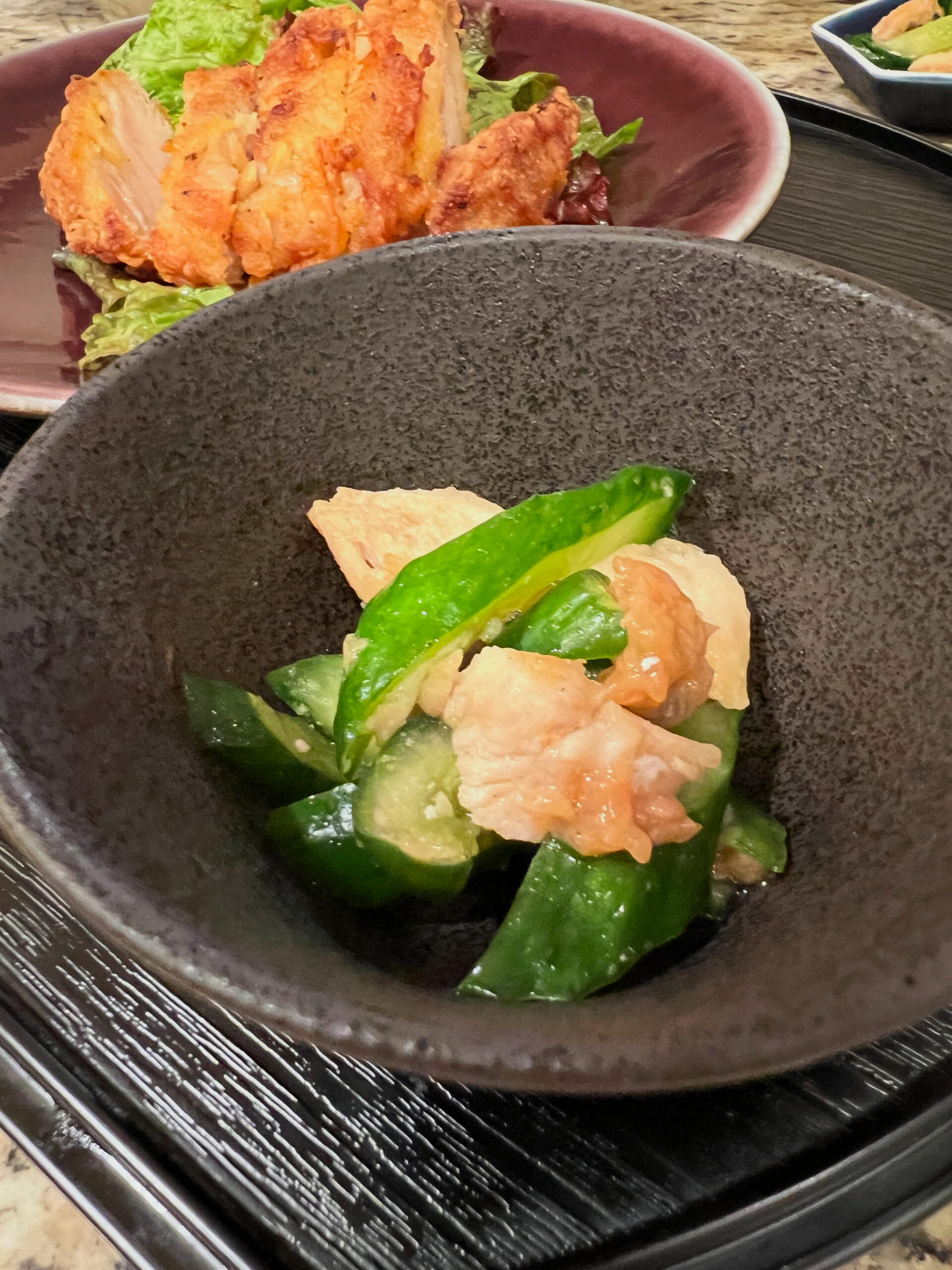 apanese chicken and cucumber salad served in a black bowl