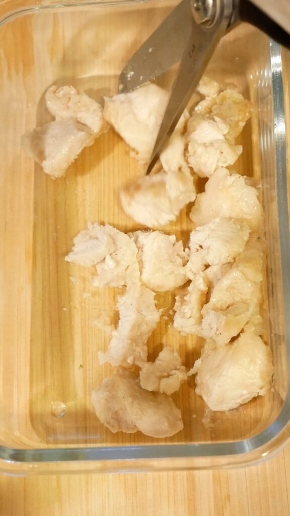 Cutting cooked chicken breast into bite-sized pieces