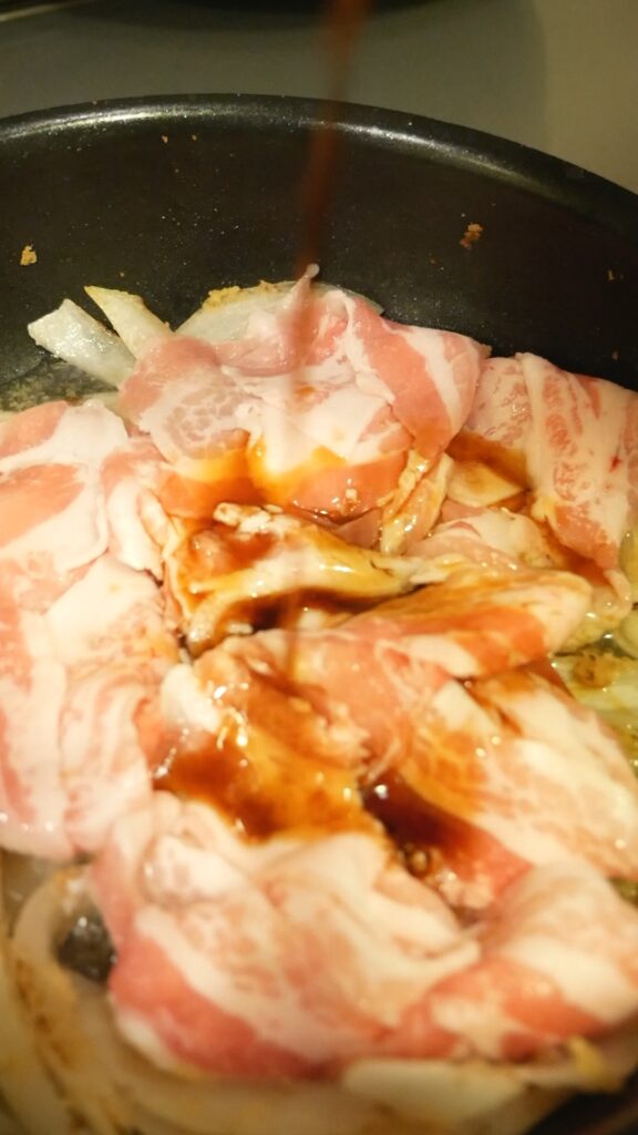 フライパンで豚肉に調味料を加えているしょうが焼きの工程