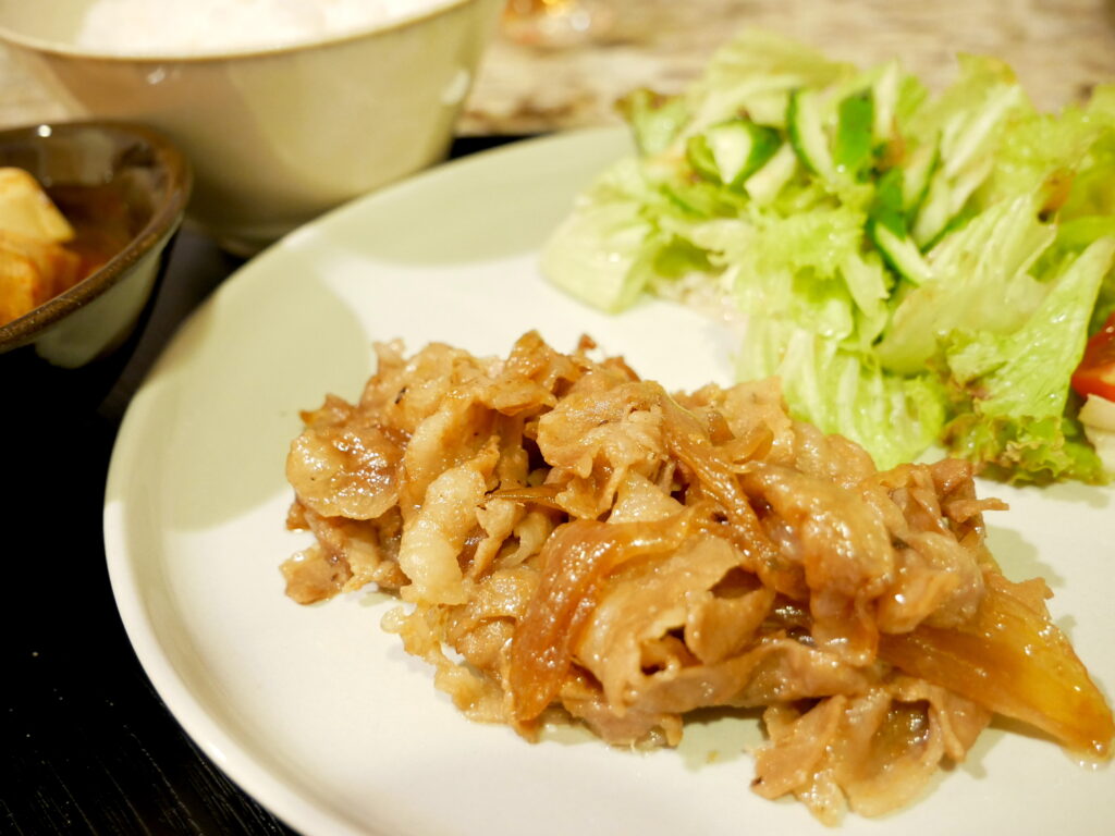 A plate of shogayaki with lettuce salad, rice, and miso soup