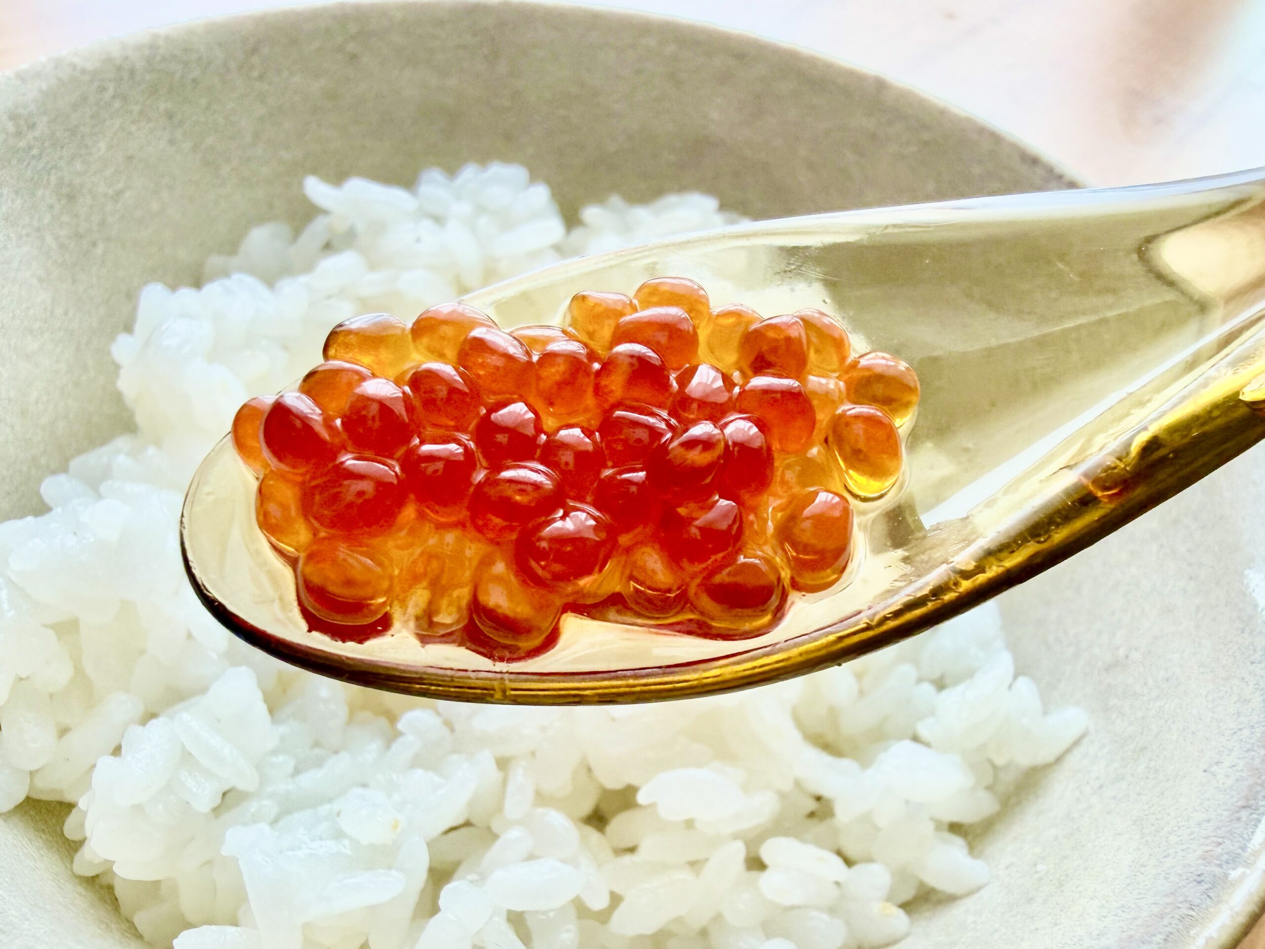 透明なスプーンに盛られた自家製いくらを白いご飯にのせた様子