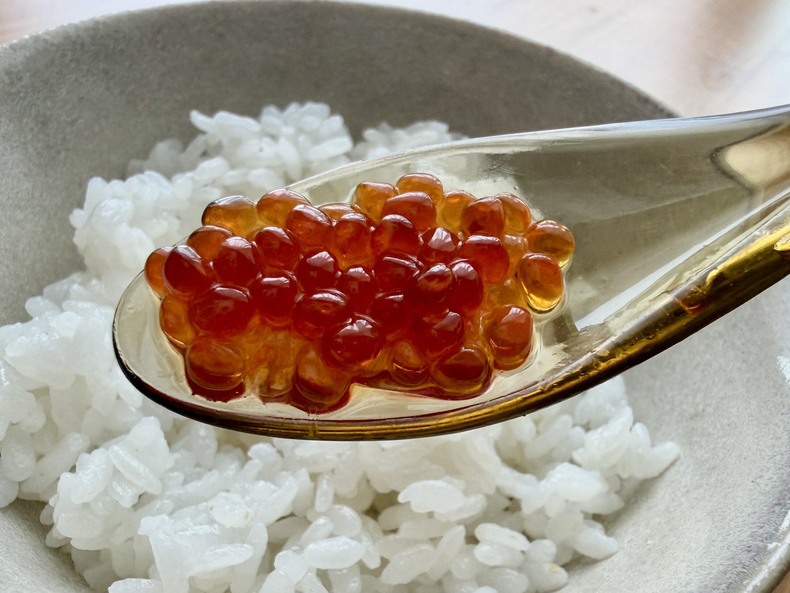透明なスプーンに盛られた自家製いくらを白いご飯にのせた様子