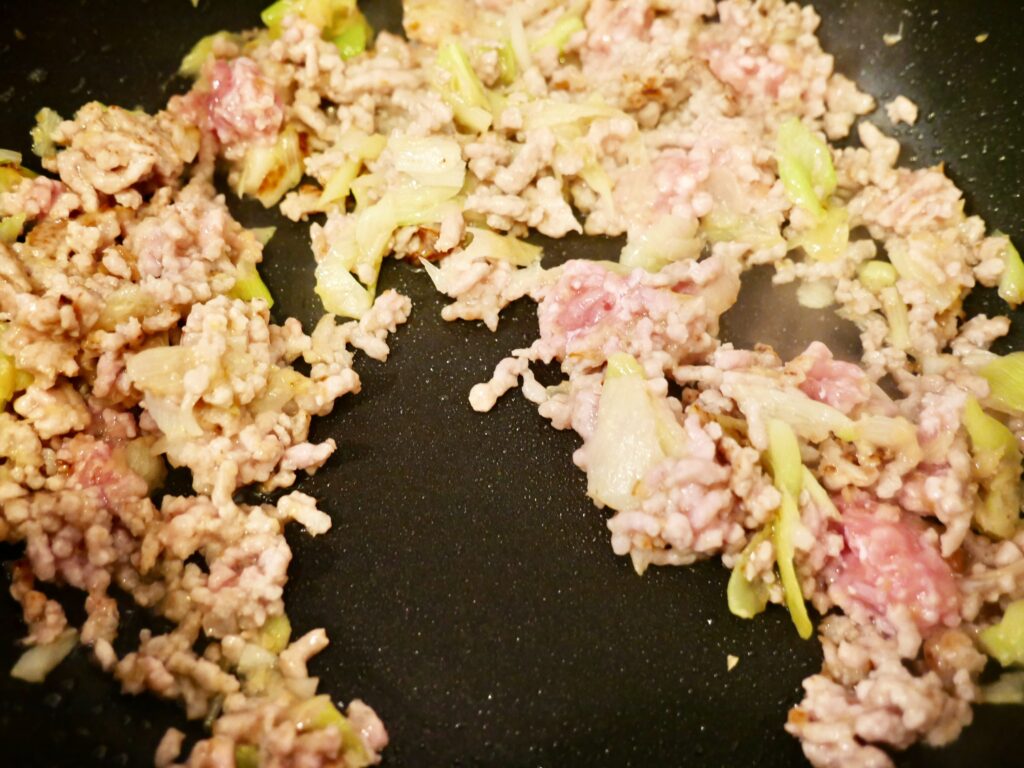 ネギと生姜の香味と一緒に豚ひき肉を炒めている工程写真