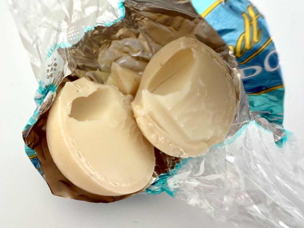 リンツのシナモンスワールを割った断面。ホワイトチョコレートの中にとろけるフィリングが見える。
