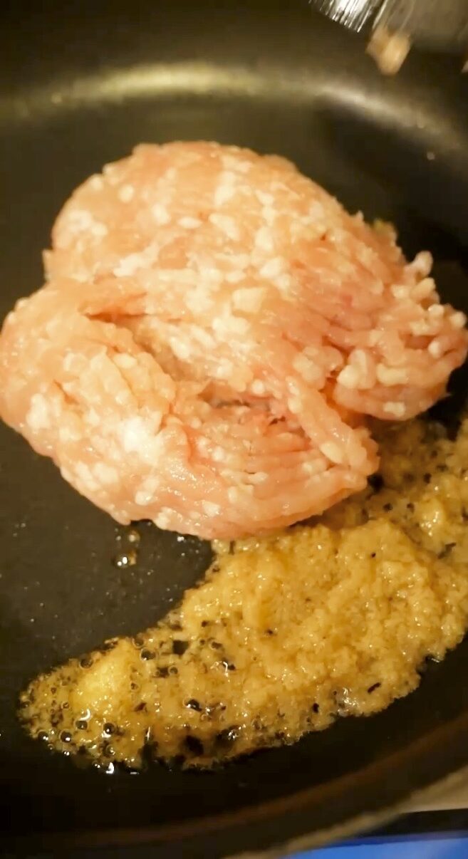 炒めた生姜の横に鶏ひき肉を入れ、そぼろ作りを始める工程。