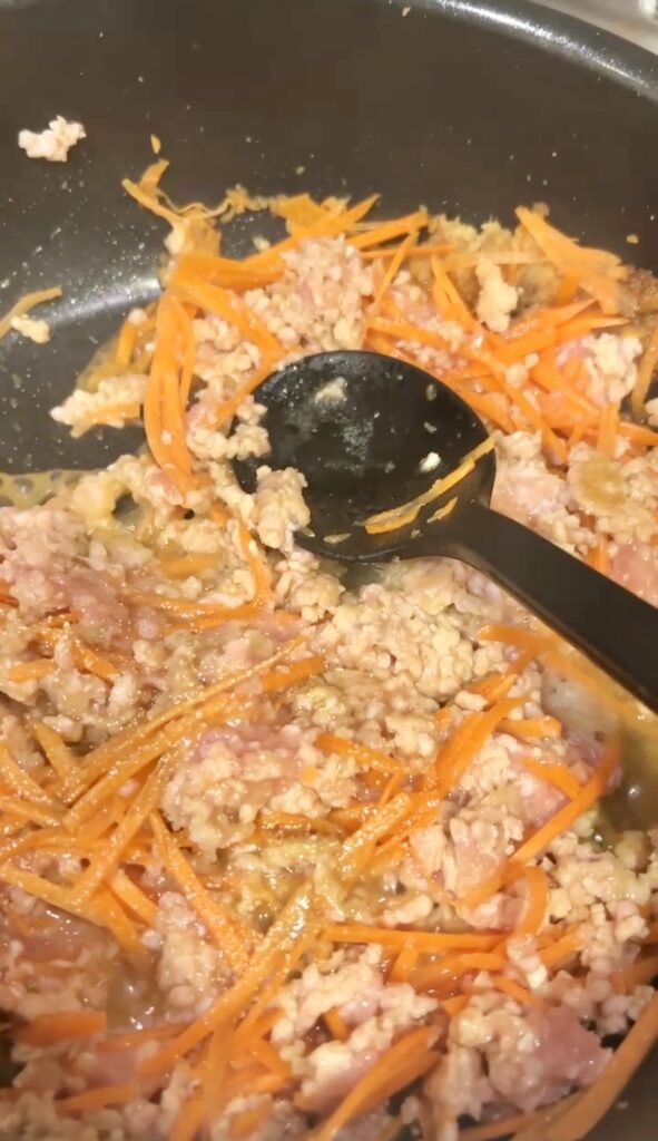千切りにしたにんじんと鶏ひき肉をフライパンで炒めているこぎつねごはんの工程