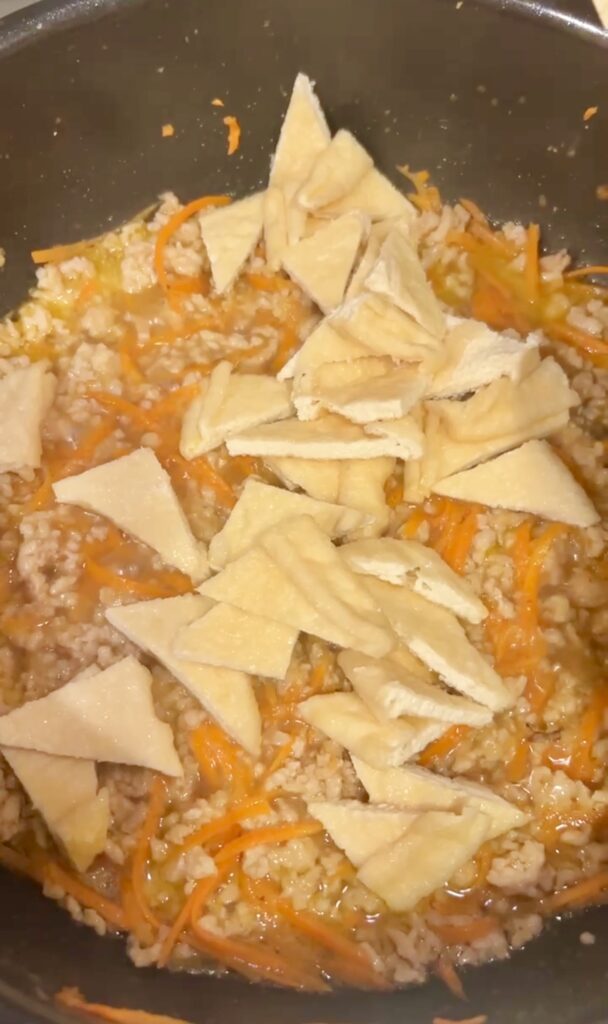 三角形に切った油揚げをフライパンに加えて煮ているこぎつねごはんの工程