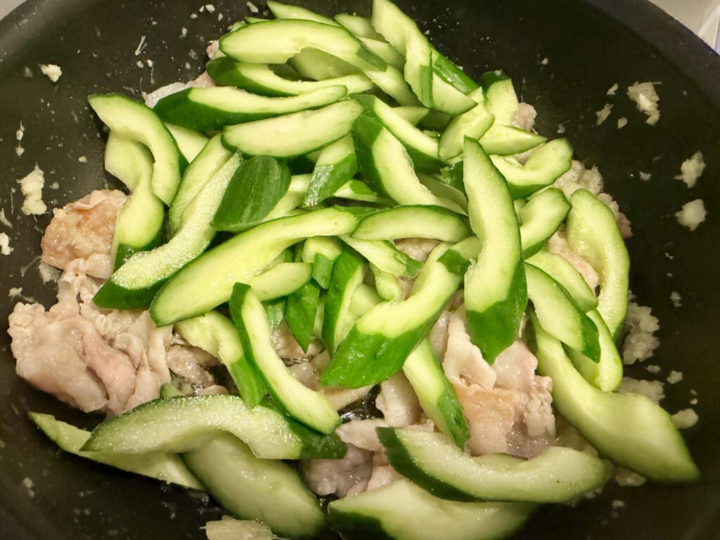 豚肉にきゅうりを加えて炒める