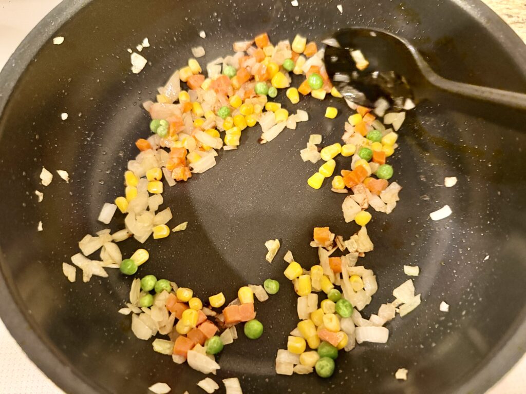 たまねぎとミックスベジタブルを炒めているフライパン