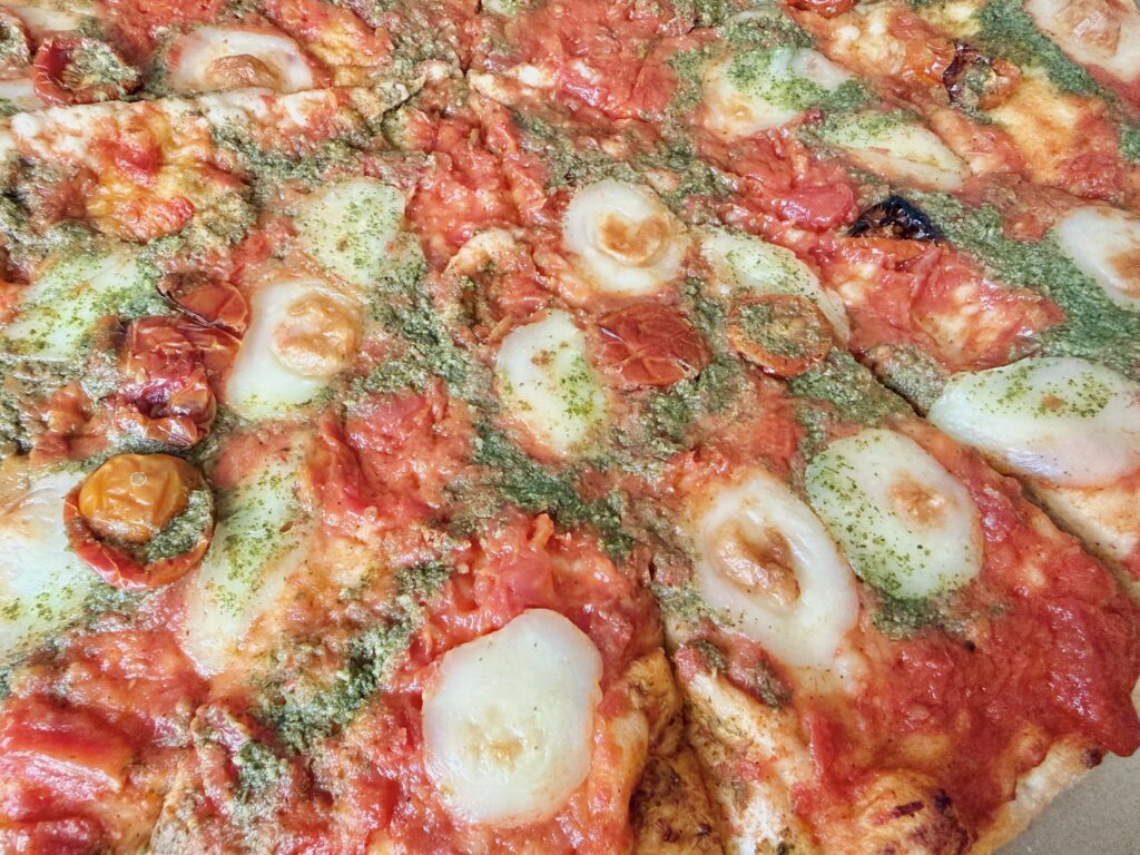 コストコ フードコートのマルゲリータピザをアップで撮影した写真。モッツァレラチーズとバジルソースがよく分かる