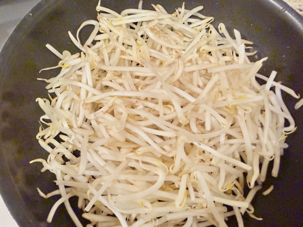 フライパンにもやしをたっぷり広げた下準備の工程写真