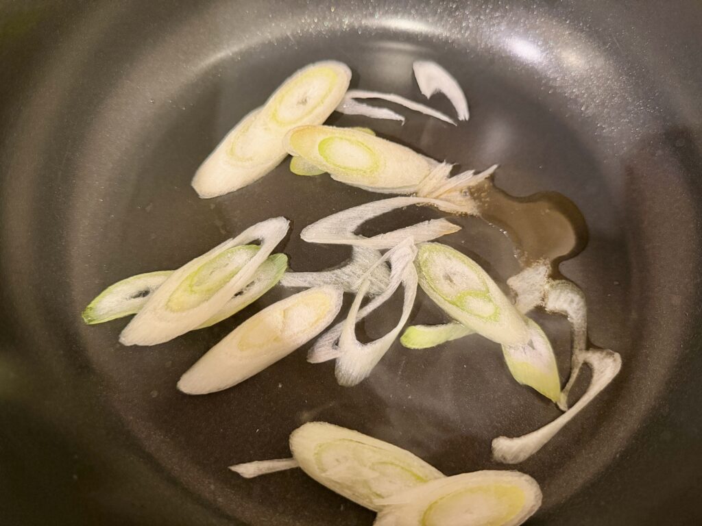 ごま油で長ネギを炒めて香りを出している様子