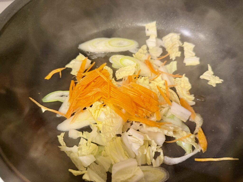 千切りにした人参を加えて炒めている工程写真