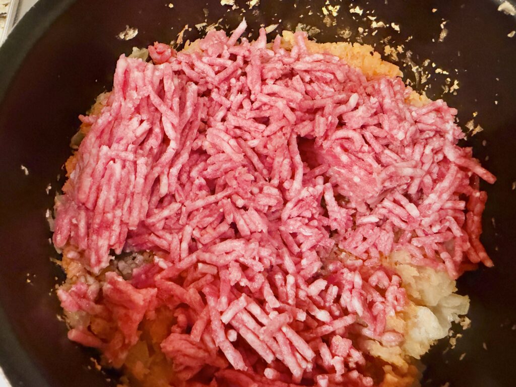 炒めた玉ねぎとにんじんに合挽き肉を加える工程