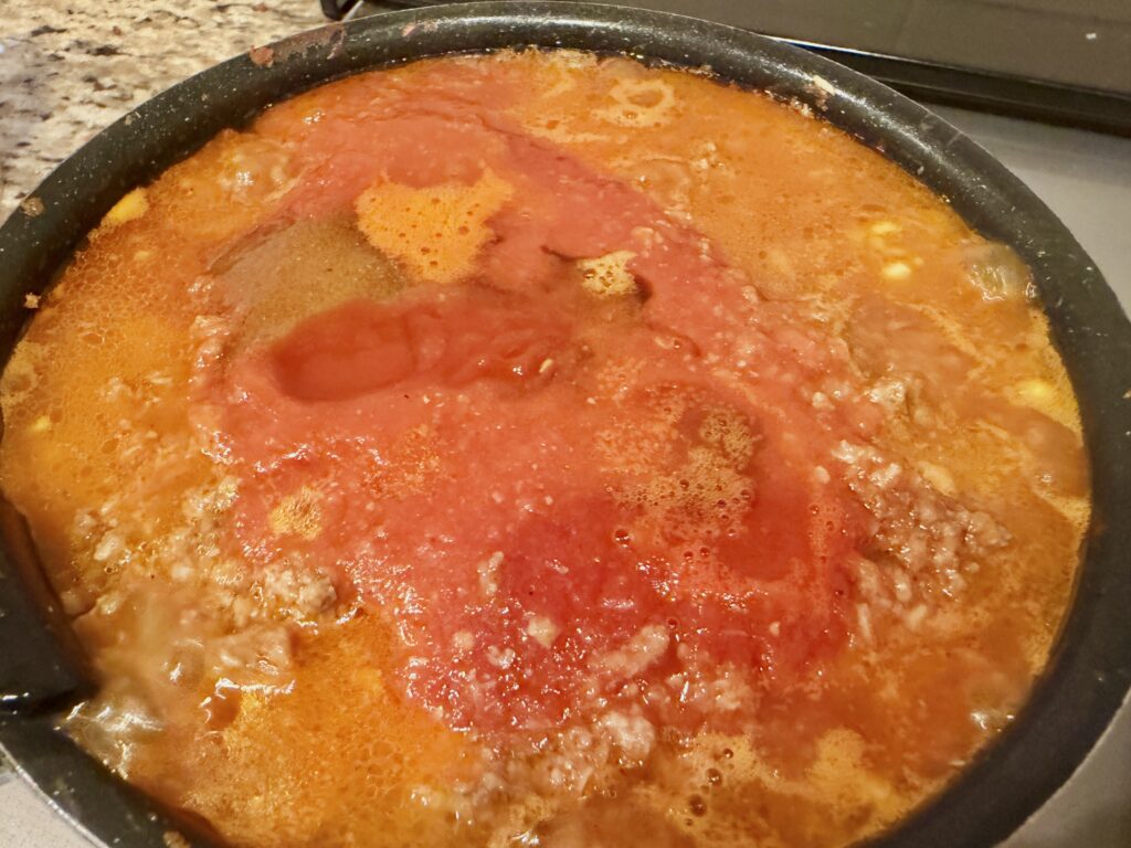 ミートソースに水とケチャップなどの調味料を加える工程