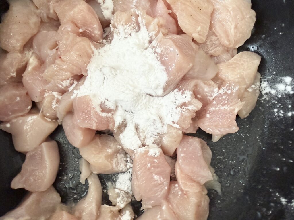 下味をつけた鶏胸肉に片栗粉を加えている様子