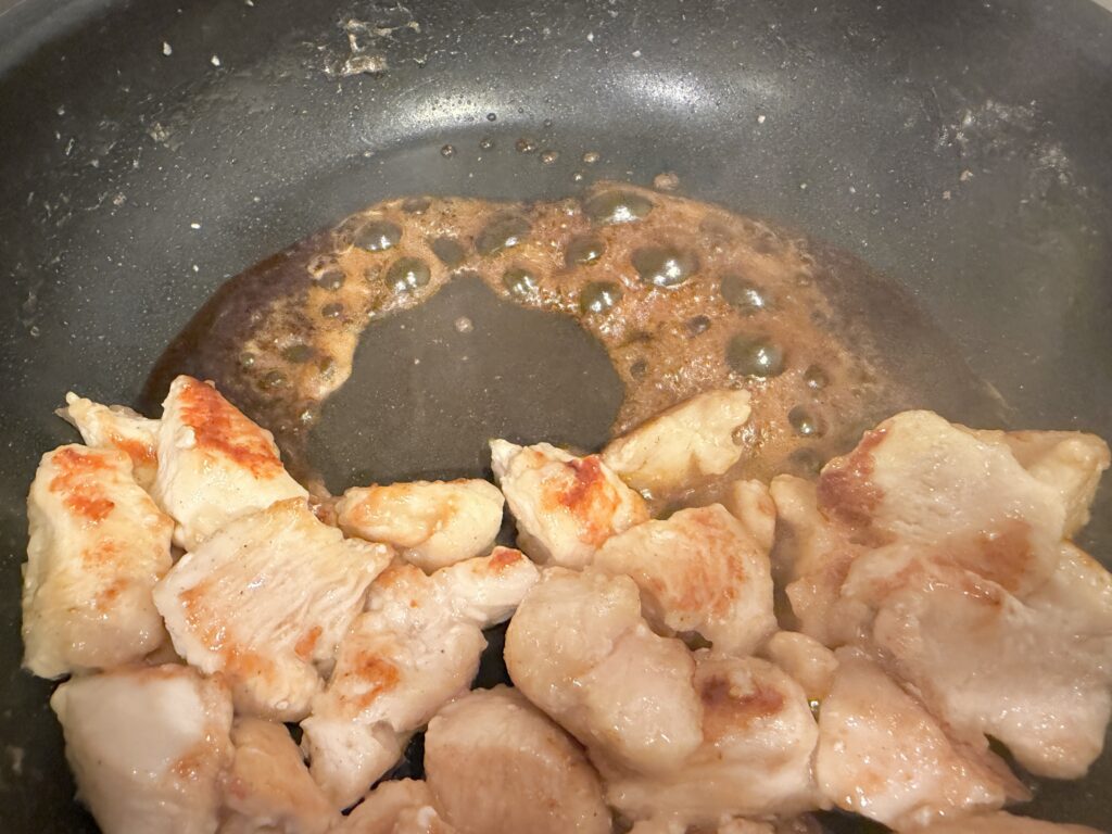 フライパンで甘酢ダレを加えている鶏むね肉