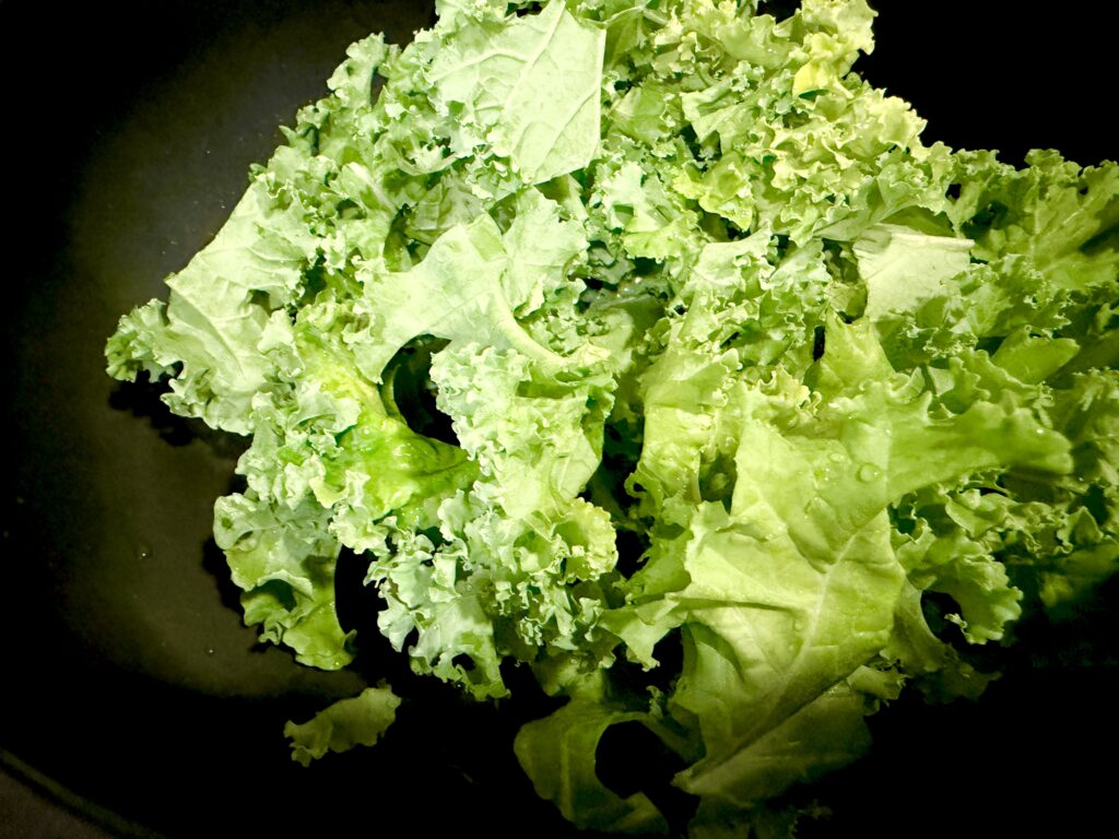 フライパンに食べやすく切った生のケールを加えた様子
