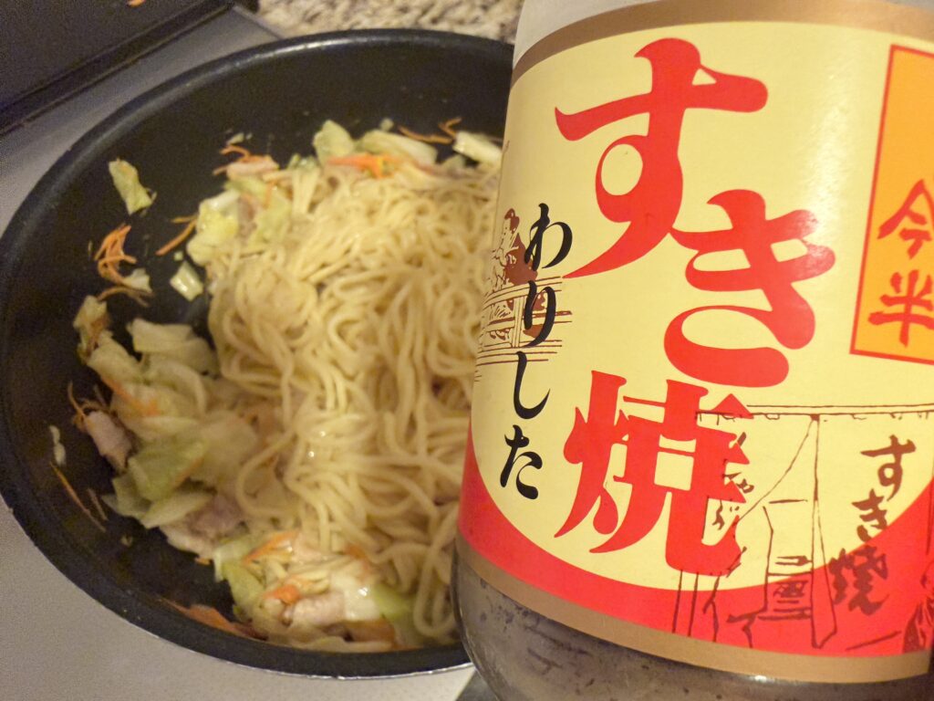 焼きそばにすき焼きのたれを加える様子