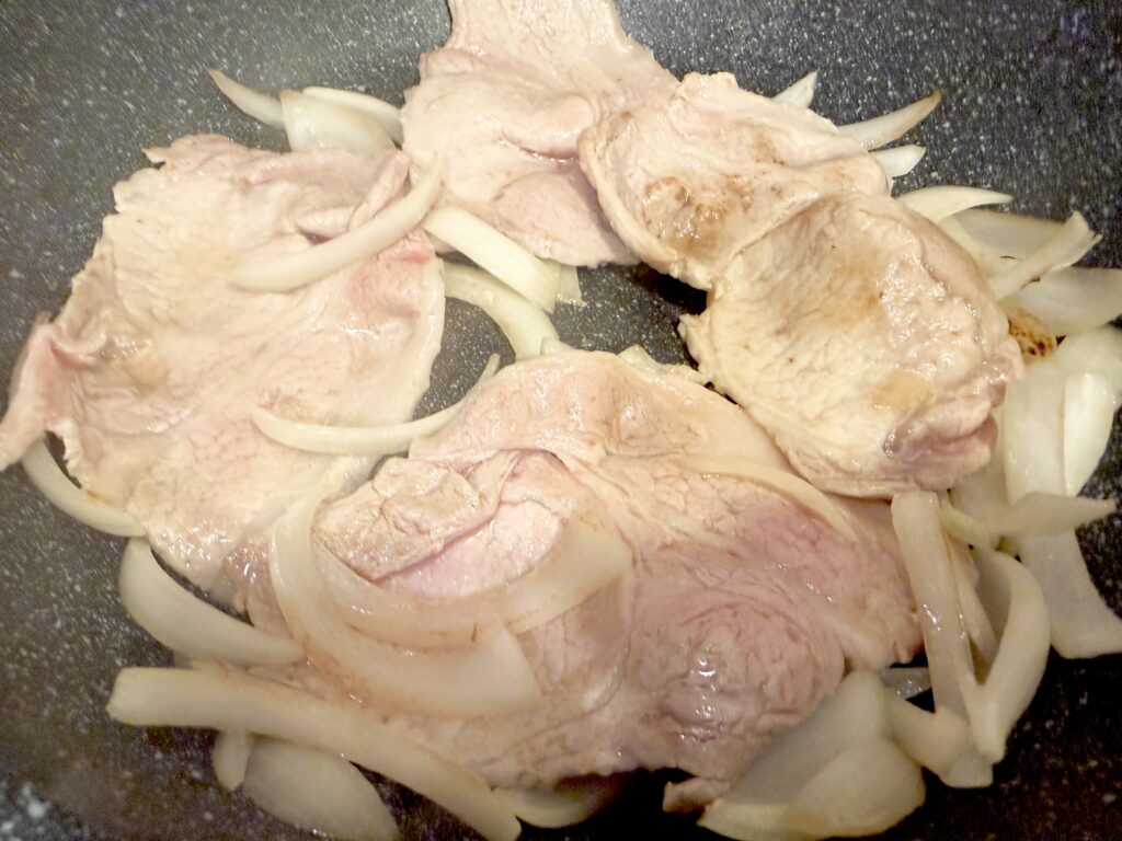 豚肩ロース肉と玉ねぎをフライパンで焼いている途中