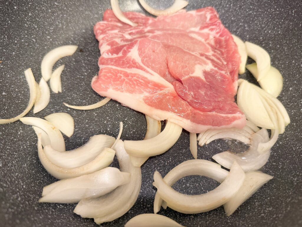 フライパンに豚肩ロース肉と玉ねぎを一度に入れた様子